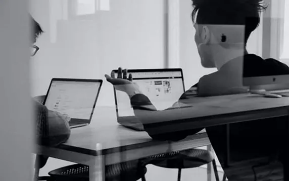 A person working on laptop at table in an office.